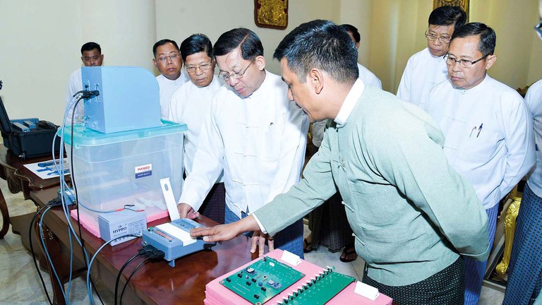 အီလက်ထရွန်နစ် မဲပေးစနစ်အသုံးပြုပုံနှင့် စက်ပိုင်းဆိုင်ရာများကို ကြည့်ရှုနေသည့် စစ်ကောင်စီခေါင်းဆောင် ဗိုလ်ချုပ်မှူးကြီးမင်းအောင်လှိုင်အား ၂၀၂၃ ခုနှစ် ဖေ‌ဖော်ဝါရီလ ၉ ရက်နေ့က တွေ့ရစဉ်။ (Photo: Myanmar Military)