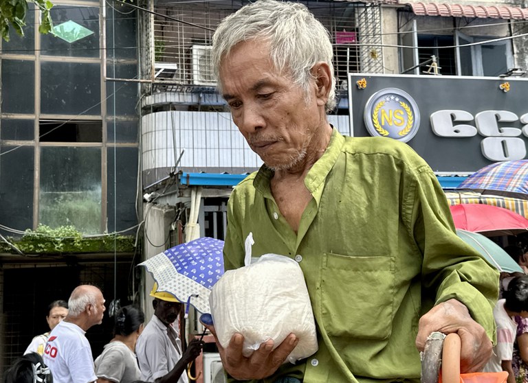 ၂၀၂၃ ခုနှစ် သြဂုတ်လ ၂၇ ရက်နေ့က ရန်ကုန်တိုင်း သင်္ဃန်းကျွန်းမြို့နယ် လေးထောင့်ကန်လမ်းမပေါ်မှာ ဆန်နဲ့ ကြက်ဥ ဈေးလျှော့ရောင်းတာကို လာရောက်ဝယ်ယူသူတစ်ဦးကို တွေ့ရစဉ်။
