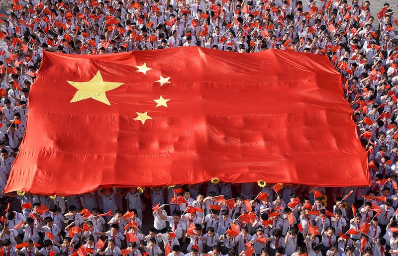 2019 年 9 月 1 日,在中国河北省邯郸市新学期开始的活动中,小学生举着一面巨大的中国国旗演奏一首名为“我和我的国家”的歌曲。(路透社)