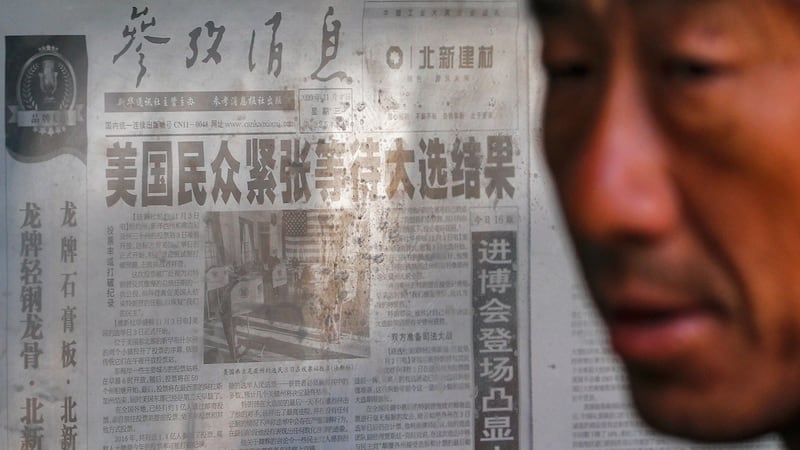 2020年11月5日,一名男子站在北京新华社官方报章头条附近,报道有关美国总统大选。(AP)