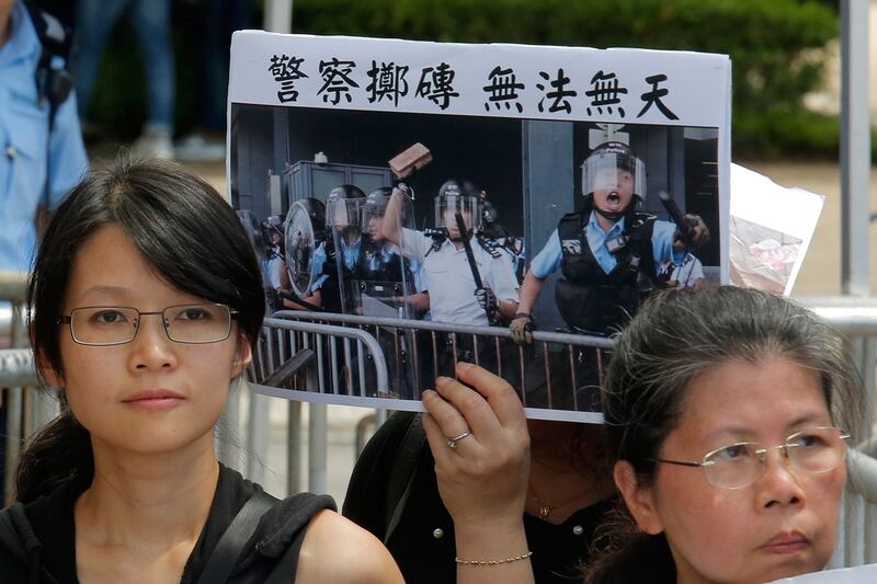 2019年6月20日,来自示威学生的父母们和宗教的各种活动团体在警察总部外抗议,示威群众举着标语牌“警察投掷砖 无法无天”。(美联社)