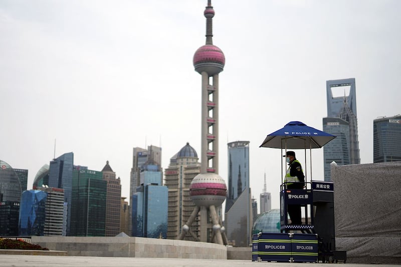 上海浦东地区采取封锁措施,一名安保人员在黄浦江对岸陆家嘴金融区的建筑物前站岗。(路透社)