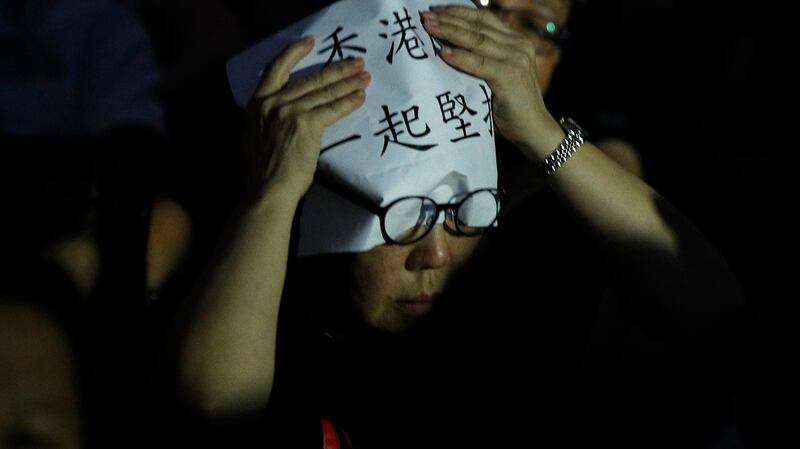 一名香港民众在头上放着“香港 一起坚持”的标语。(美联社)