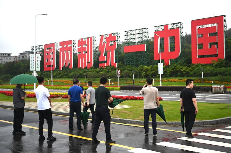 2024年5月23日,在福建省厦门市附近的海滩,游客经过一块巨大标志,上面写着"一国两制统一中国"。(法新社)