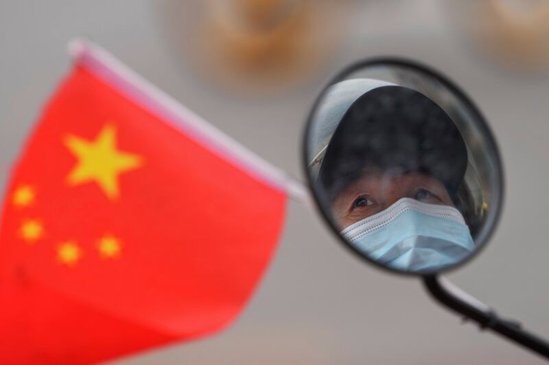 北京一名女子戴着口罩在开车。(美联社)