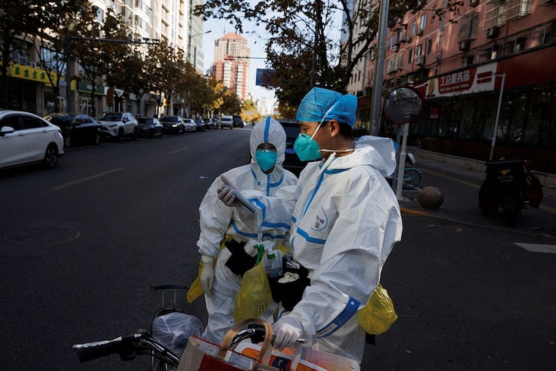 2022 年 11 月 21 日,新一波疫情也在中国各地卷土重来,防疫工作人员站在北京街上。(路透社)