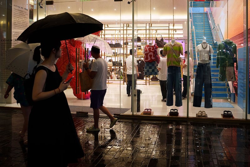2024年7月30日,人们经过北京太古里三里屯的一家服装店。(美联社)