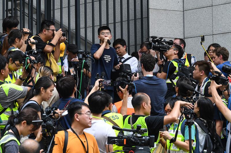 2019年6月21日,香港众志秘书长黄之锋(Joshua Wong)在警察总部外抗议时发表讲话,要求警务处处长卢伟聪撤回暴动定性,释放被捕人士。(法新社)