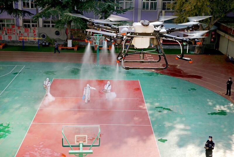 A drone sprays disinfectant over volunteers disinfecting a school following local cases of the coronavirus disease (COVID-19) in Lanzhou, Gansu province, China October 27, 2021. Credit: Reuters