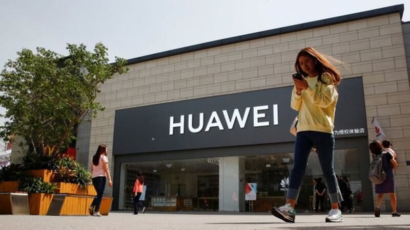 2019年5月16日,一名女子手拿手机走过北京一家华为商店。(路透社)