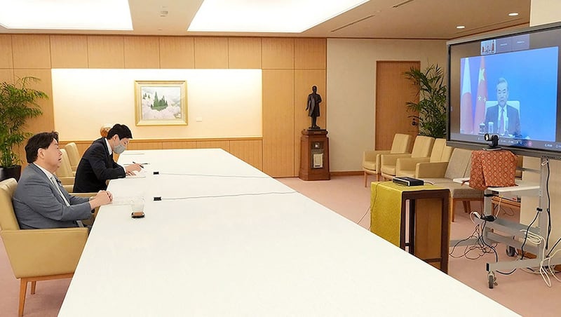 2022 年 5 月 18 日,日本外相林芳正(左)在东京通过视频连线与中国国务委员兼外长王毅(右)交谈。(法新社)