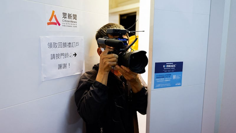 香港众新闻因为过去两年社会遽变环境恶化,宣布即将熄灯。图为,2022 年 1 月 3 日,一名媒体成员在香港《众新闻》标志旁。(路透社)