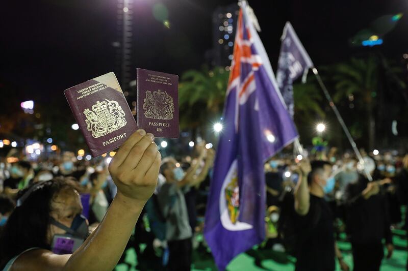 A protester raises his British National Overseas passports during a candlelight vigil to mark the 31st anniversary of the Tiananmen Square crackdown, in Hong Kong, June 4, 2020. (Tyrone Siu/Reuters)