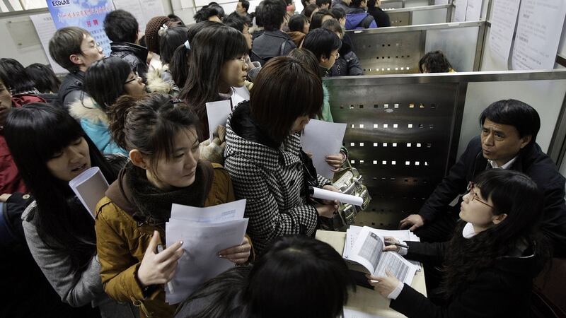 资料图片:求职者在北京的大学毕业生招聘会上排队申请职位空缺。(美联社)