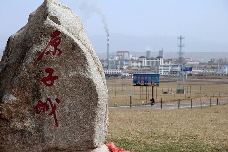 2007 年 5 月 12 日,中国青海省海盐市,在通往中国第一个核武器基地的道路上,一块纪念碑石标志着“核城”,背景是一座新的工业城市,该基地已解密并向游客开放。(法新社)