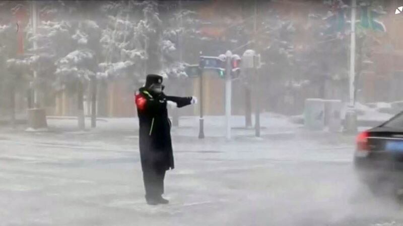 2023年1月22日,黑龙江省漠河市下雪公路上的交通警察在指挥交通。(路透社视频截图)