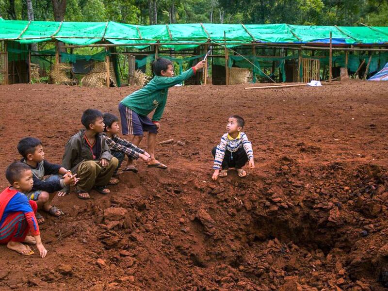 Boys play at a bomb site after an aerial attack on a refugee camp in Western Dim So, Kayah State, Myanmar, June 4, 2023.